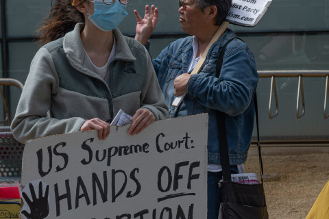 Asian American demonstrators sign says "Supreme Court: Hands Off the Abortion Pill"