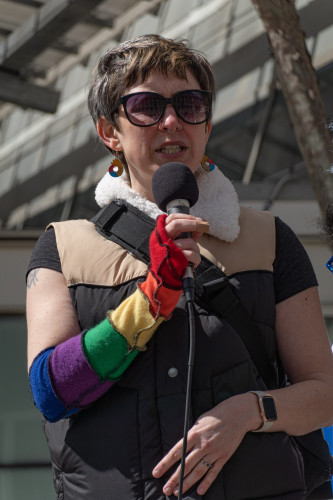 Protester with rainbow colored long gloves at the microphone