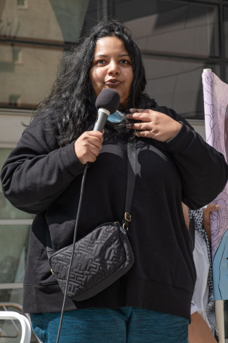 Demonstrator with long black hair and dressed in black at mic
