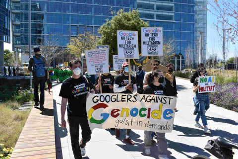 marchers in black with Google equals Genocide banner